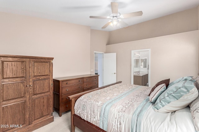 bedroom featuring light carpet, vaulted ceiling, connected bathroom, and a ceiling fan