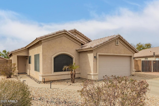 view of front of home featuring a tile roof, stucco siding, fence, a garage, and driveway