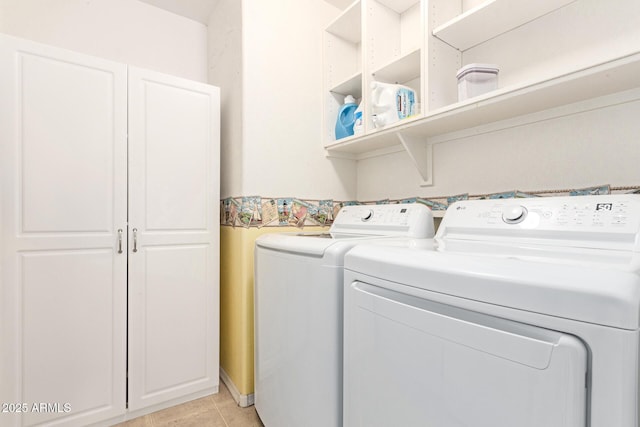 clothes washing area with cabinet space, light tile patterned floors, and washing machine and clothes dryer