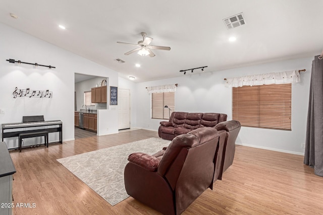 living room featuring light wood-type flooring, ceiling fan, visible vents, and vaulted ceiling