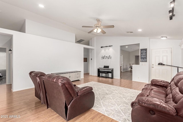 living area featuring vaulted ceiling, visible vents, light wood-style flooring, and a ceiling fan