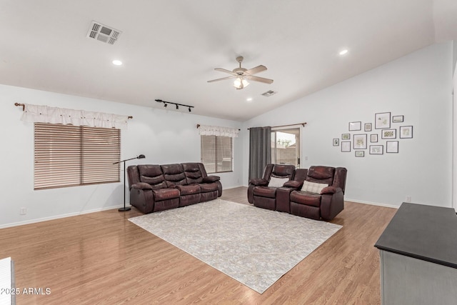 living area featuring light wood-style floors, ceiling fan, visible vents, and vaulted ceiling