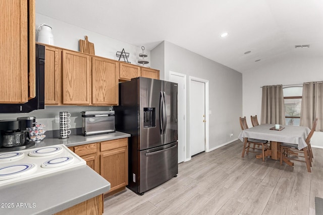 kitchen featuring light wood finished floors, light countertops, visible vents, vaulted ceiling, and stainless steel fridge with ice dispenser