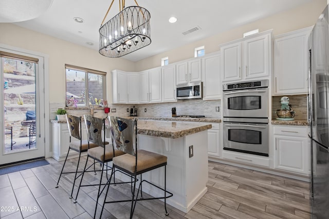 28019 N 115th Pl, Scottsdale, AZ 85262 - kitchen with stainless steel appliances, white cabinets, a breakfast bar, a kitchen island, and recessed lighting