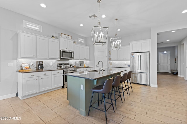 6948 E Quill St, Mesa, AZ 85207 - kitchen with appliances with stainless steel finishes, a sink, backsplash, a breakfast bar area, and a chandelier