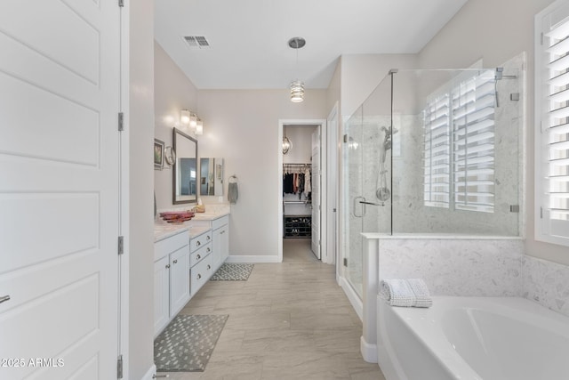 6948 E Quill St, Mesa, AZ 85207 - bathroom with vanity, a shower stall, a garden tub, a walk in closet, and baseboards