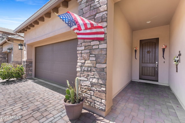 6948 E Quill St, Mesa, AZ 85207 - view of exterior entry with stone siding, stucco siding, a garage, and driveway