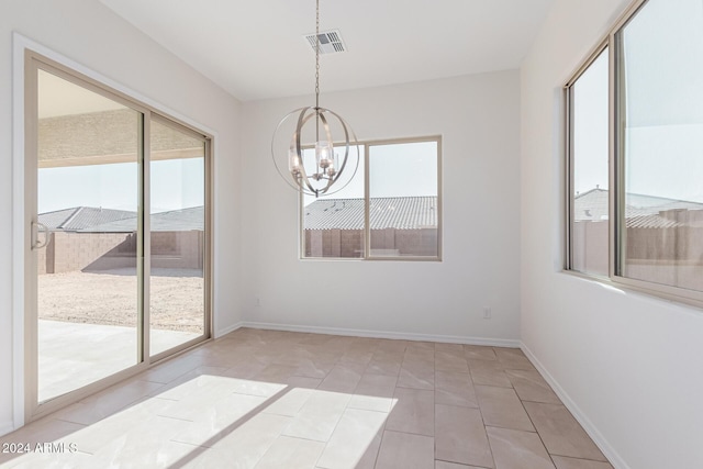 unfurnished dining area with plenty of natural light, light tile patterned flooring, and a chandelier