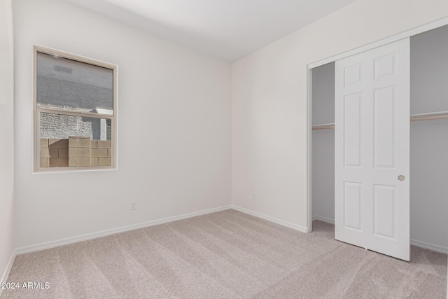 unfurnished bedroom featuring light carpet and a closet