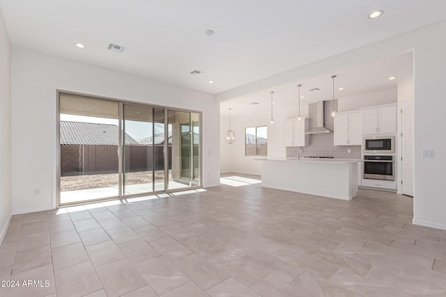 unfurnished living room with light tile patterned flooring, sink, and a wealth of natural light