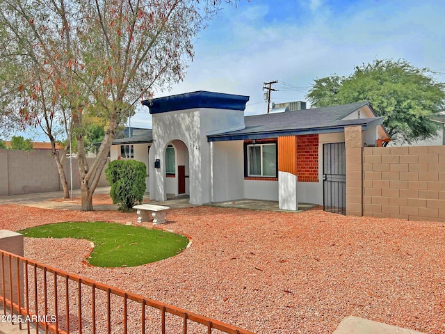 view of front facade with a patio area, stucco siding, and fence