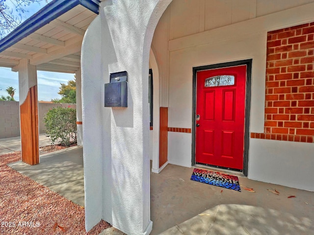 property entrance featuring fence, brick siding, and stucco siding