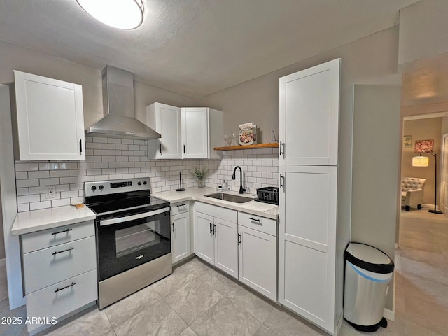 kitchen with electric range, a sink, white cabinets, wall chimney exhaust hood, and tasteful backsplash