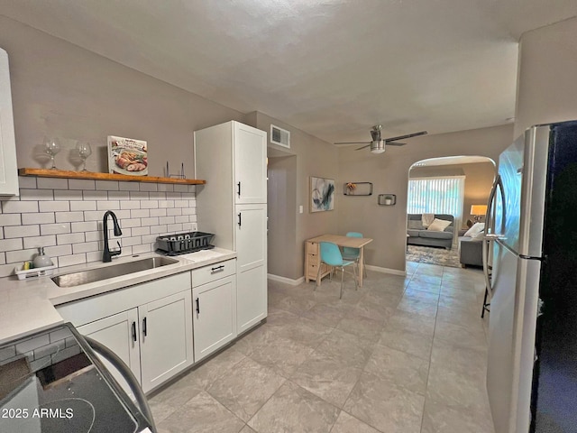 kitchen featuring visible vents, open shelves, freestanding refrigerator, a sink, and light countertops