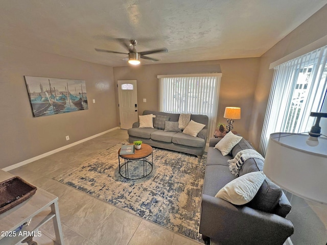 living area featuring a healthy amount of sunlight, baseboards, and ceiling fan