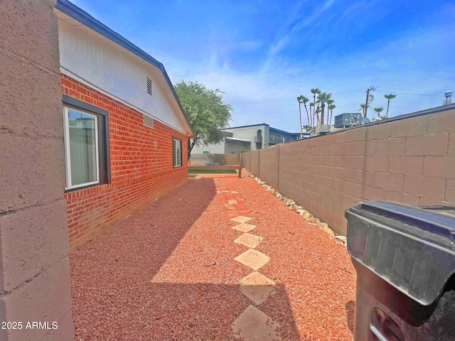 view of property exterior featuring brick siding and a fenced backyard