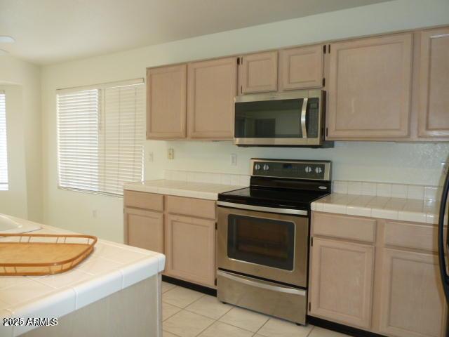 kitchen with tile countertops, light brown cabinets, and stainless steel appliances