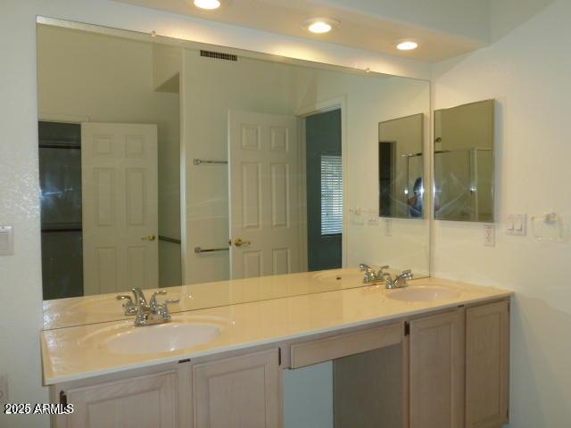 bathroom featuring double vanity, recessed lighting, and a sink