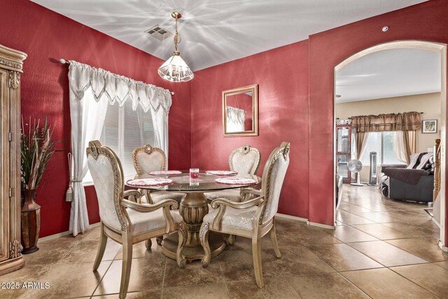 dining area with tile patterned flooring, arched walkways, visible vents, and baseboards