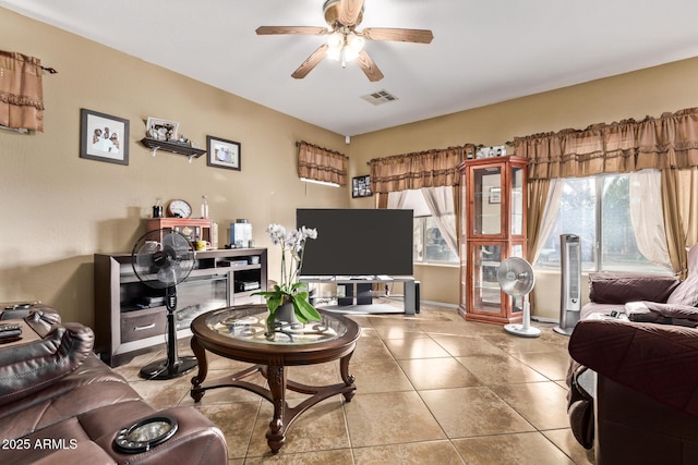 living area featuring tile patterned floors, a ceiling fan, visible vents, and baseboards