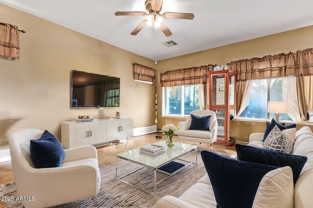 living room featuring light tile patterned floors, baseboards, visible vents, and ceiling fan