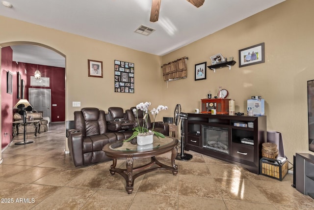 living room featuring arched walkways, visible vents, and a ceiling fan