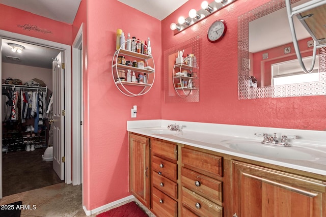 bathroom featuring a sink, a walk in closet, double vanity, and tile patterned floors
