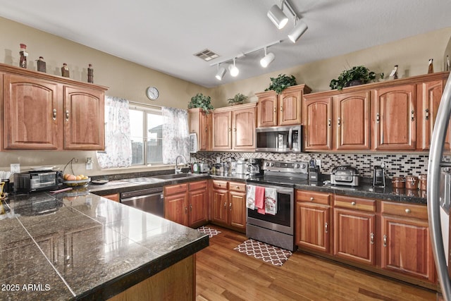 kitchen with light wood finished floors, visible vents, tile countertops, appliances with stainless steel finishes, and a sink