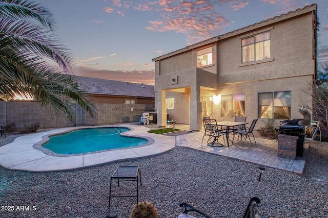 pool at dusk with a patio area, a fenced in pool, and a fenced backyard