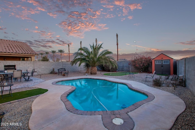 pool at dusk with outdoor dining area, a fenced backyard, an outdoor structure, a storage shed, and a patio area