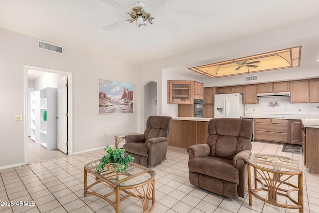 tiled living room with a tray ceiling and ceiling fan