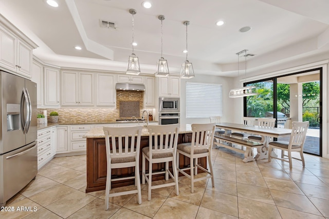 30406 N 54th St, Cave Creek, AZ 85331 - kitchen featuring stainless steel appliances, a raised ceiling, decorative backsplash, light tile patterned floors, and a kitchen island with sink