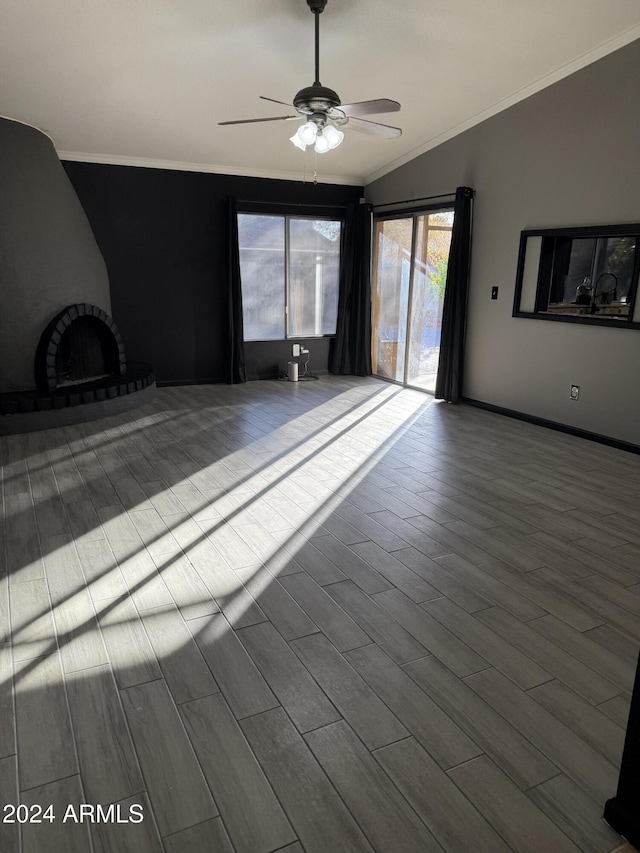 spare room featuring a brick fireplace, vaulted ceiling, ceiling fan, light hardwood / wood-style flooring, and ornamental molding