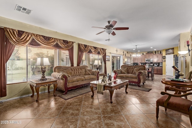 living room featuring ceiling fan with notable chandelier and dark tile patterned floors