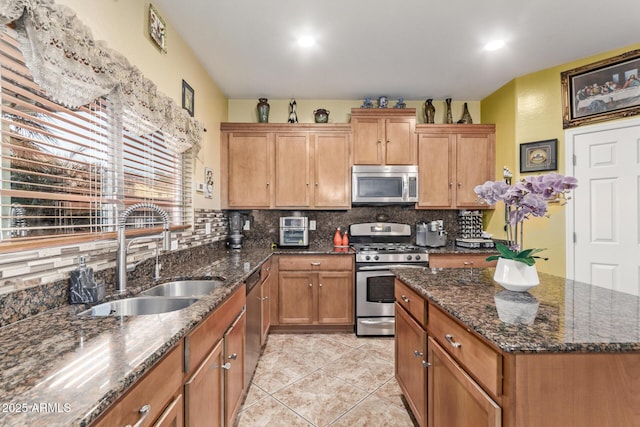 kitchen featuring tasteful backsplash, dark stone counters, stainless steel appliances, sink, and light tile patterned floors