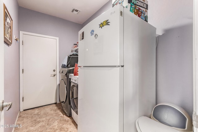 laundry room featuring washing machine and clothes dryer and light tile patterned floors