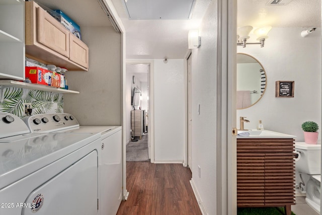 clothes washing area featuring sink, washing machine and clothes dryer, and dark hardwood / wood-style floors