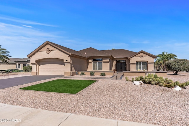 view of front facade with a garage, aphalt driveway, and stucco siding