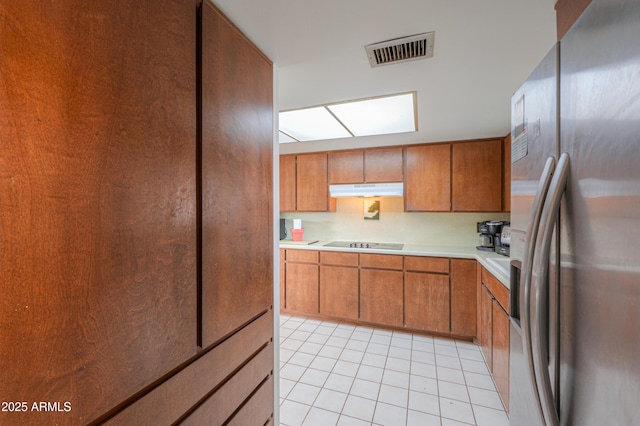 kitchen featuring black electric stovetop, light tile patterned floors, and stainless steel fridge with ice dispenser