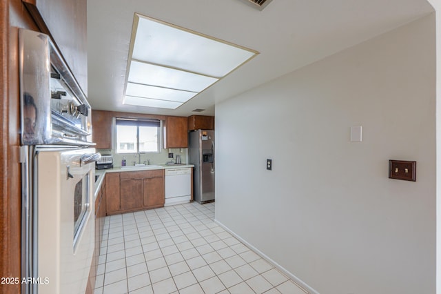 kitchen with stainless steel fridge with ice dispenser, sink, light tile patterned floors, wall oven, and white dishwasher