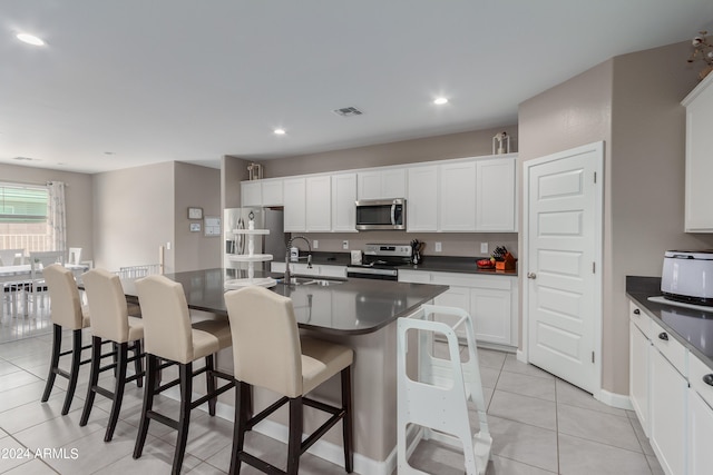 kitchen with a kitchen island with sink, sink, stainless steel appliances, and white cabinetry