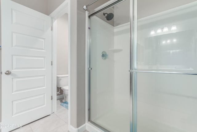 bathroom with tile patterned flooring, toilet, and an enclosed shower