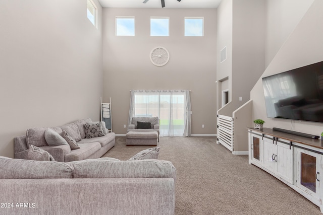 carpeted living room featuring ceiling fan, a towering ceiling, and a healthy amount of sunlight