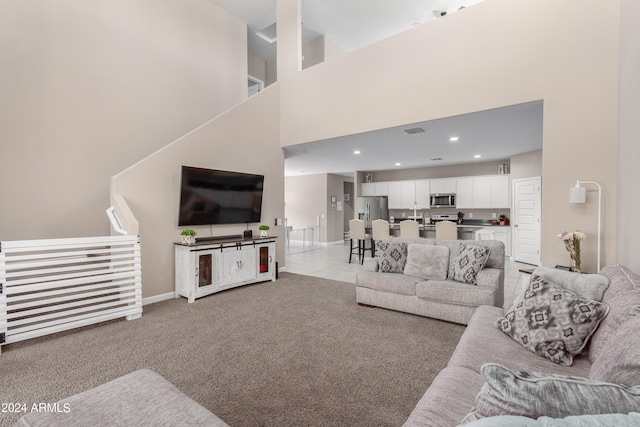 living room featuring a high ceiling, light colored carpet, and sink