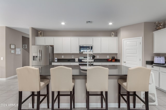 kitchen with white cabinets, appliances with stainless steel finishes, and a kitchen island with sink