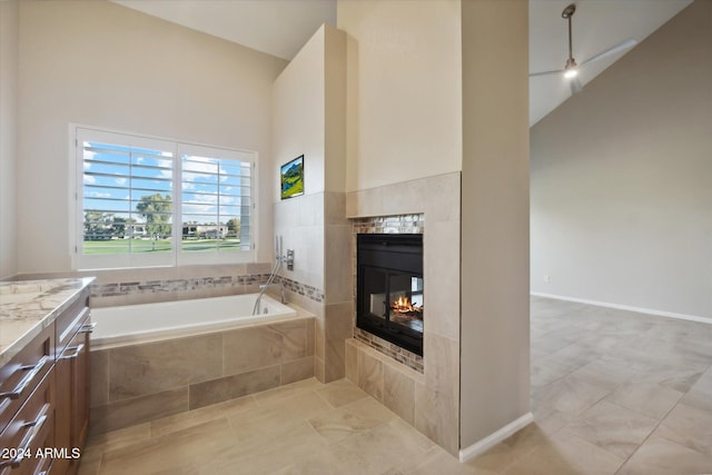 bathroom with a towering ceiling, vanity, and tiled tub