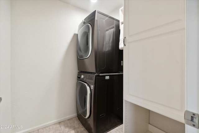 laundry area with light tile patterned floors and stacked washer and clothes dryer