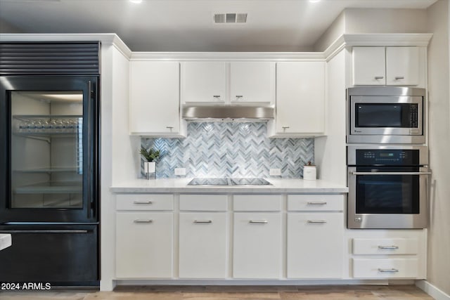 kitchen featuring white cabinets, decorative backsplash, and built in appliances