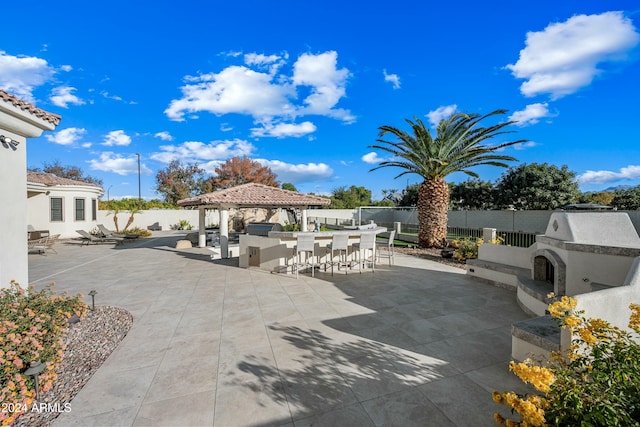 view of patio with a gazebo, a bar, and exterior fireplace