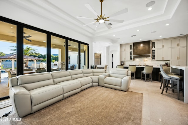 living room featuring a raised ceiling, ceiling fan, and sink